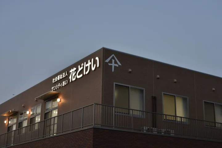 介護施設の建物外観。茶色い壁に施設名の看板が見える夕方の撮影